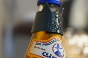 Ein grauer Katzenohren Mate Tag mit meinem Namen an einer Club-Mate Flasche.